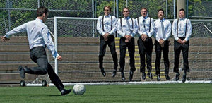 Groom kicking soccer ball at Groomsman